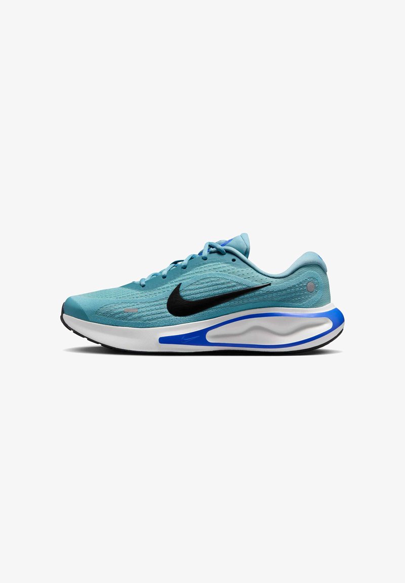 Chaussure de sport bleu clair avec une tige texturée, logo Swoosh noir, semelle intermédiaire blanche avec des accents bleus, et semelle extérieure noire plate.