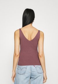 Geribbelde, burgundy tanktop met een diepe V-achterkant. De stof is zacht, aansluitend en eenvoudig, en past goed bij hoge taille denim jeans.