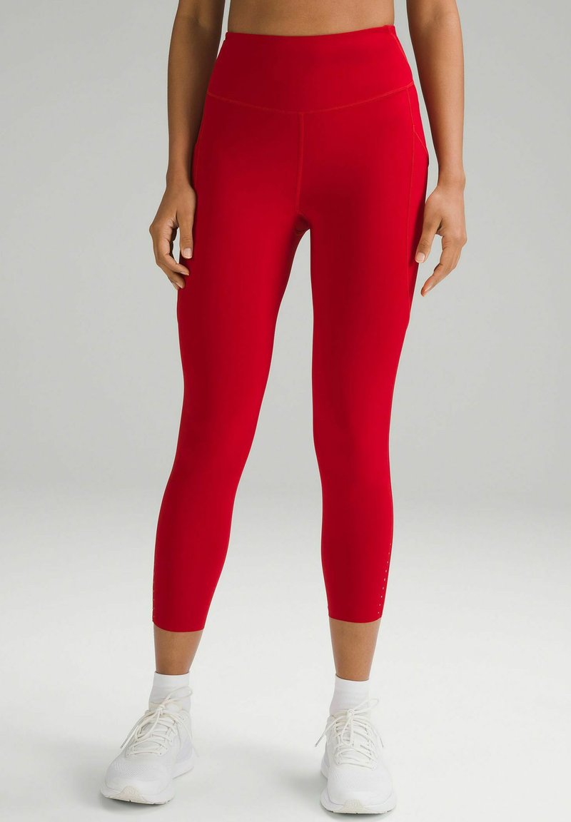 Leggings active roșii, cu talie înaltă, realizate dintr-un material elastic cu o textură fină, având buzunare laterale și cusături detaliate.