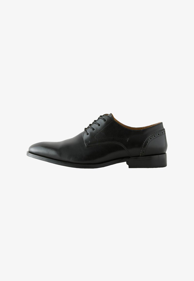 Chaussure Oxford pour homme en cuir noir avec laçage fermé, talon bas et perforations décoratives sur le talon et les côtés.