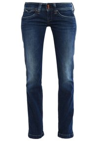 Jean slim bleu foncé avec poches avant, rivets en cuivre et fermeture double bouton, montrant une légère décoloration sur les cuisses et les genoux.