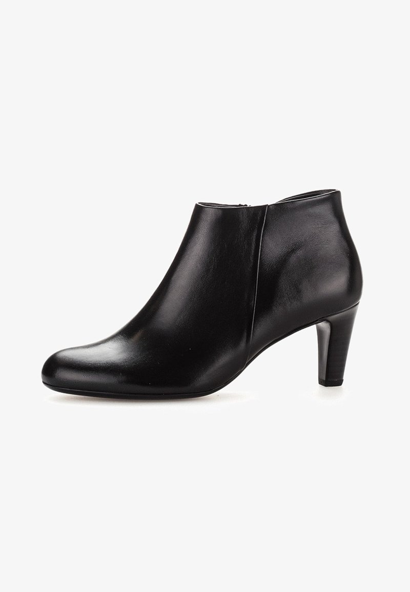 Bottine en cuir noir avec un talon fin de hauteur moyenne et un bout arrondi lisse, fermeture éclair latérale, design minimaliste.