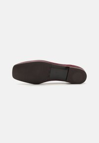Burgunderfarget flatsko med en glatt, strukturert overflate, med rund tå og en svart gummisåle. Minimalistisk design, ingen synlige detaljer.