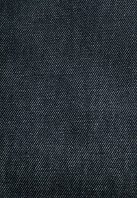 Dunkles Denimgewebe mit einem diagonalen Webmuster und subtilen hellen Flecken, die einen strukturierten Look verleihen.