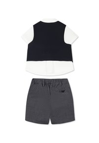 Completo a due pezzi composto da una camicia bianca con un gilet nero e pantaloni corti grigi a trama con vita elasticizzata e dettaglio sulla tasca posteriore.