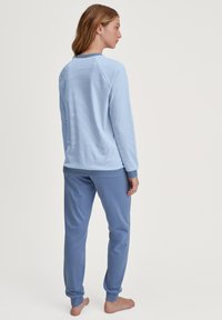 Lichtblauwe pyjama set met een getextureerde lange mouwen top met een ronde halslijn en effen blauwe broek met boorden bij de enkels.