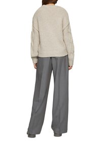 Cremiger Strickpullover mit entspannter Passform und überschnittenen Schultern, kombiniert mit hochtaillierten grauen weit geschnittenen Hosen. Strukturiertes Gewebe und gerippte Bündchen.