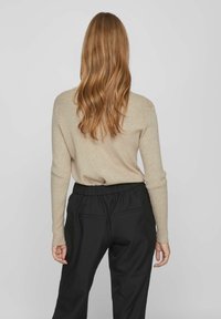 Pulover bej cu dungi, cu mâneci lungi, combinat cu pantaloni negri, cu talie elastică, având buzunare la spate. Paletă de culori simplă și neutră.