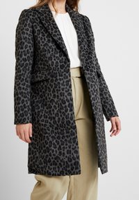 Abrigo largo de estampado de leopardo en tejido gris y negro, con cuello de muesca, dos bolsillos frontales y un corte ajustado.