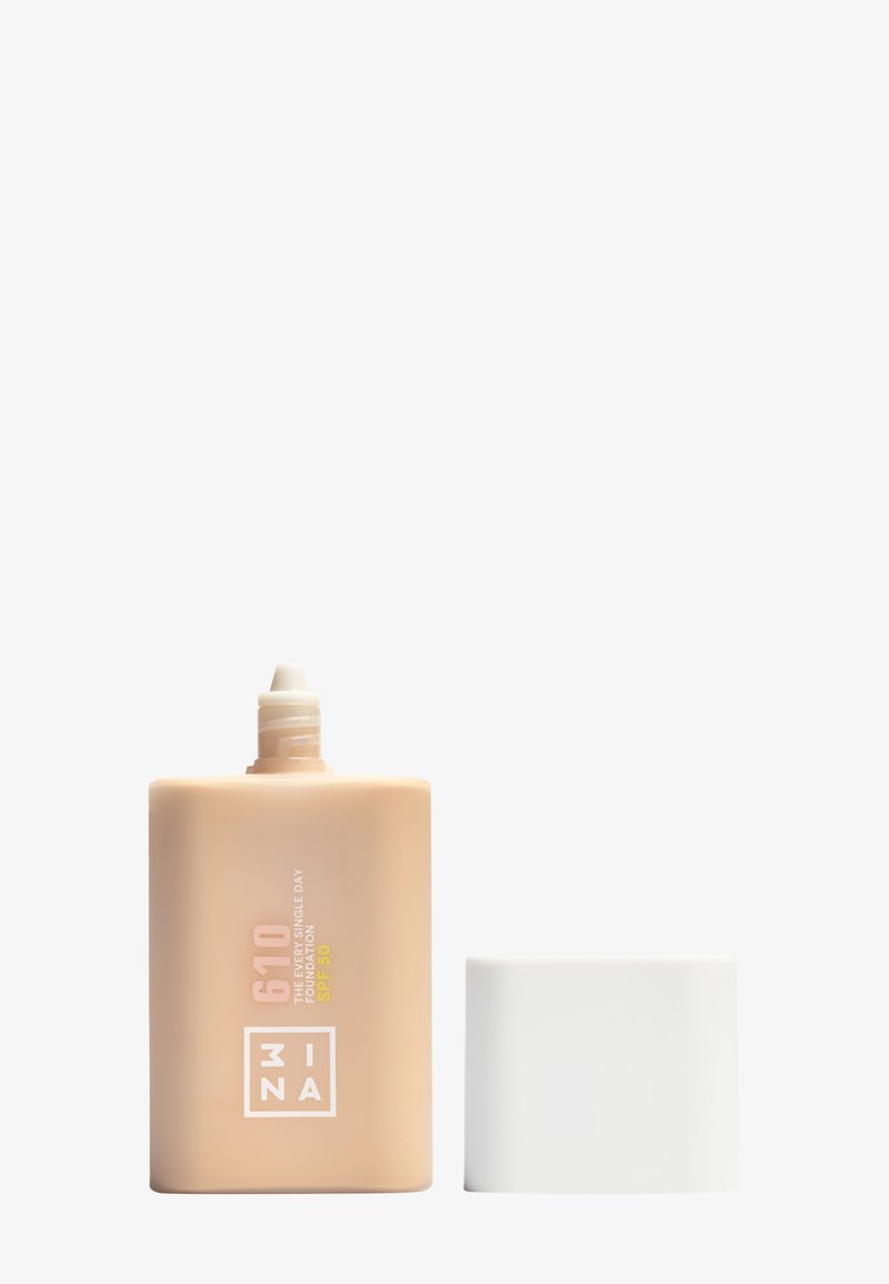 Foundationfles met een rechthoekig ontwerp in zacht beige, voorzien van een schroefdop en een reliëflogo, gelabeld met SPF 50, tint 610.