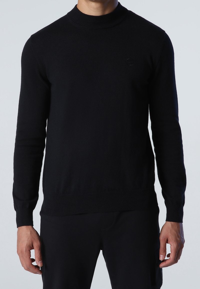 Black sweater with a high neckline, long sleeves, and ribbed cuffs. Made from a soft fabric. Features a small, subtle logo on the chest.
