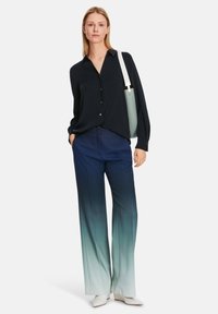 Navy-blaues Hemdbluse, weite Hosen mit ombre Effekt von Dunkelblau zu Hellblau und weiße spitz zulaufende Schuhe. Inklusive einer mintgrünen Tasche.