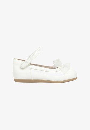 Zapato de bailarina de charol blanco con puntera redonda, cinturilla al tobillo y un lazo decorativo de tul en la parte delantera. Suela de goma de color beige claro.