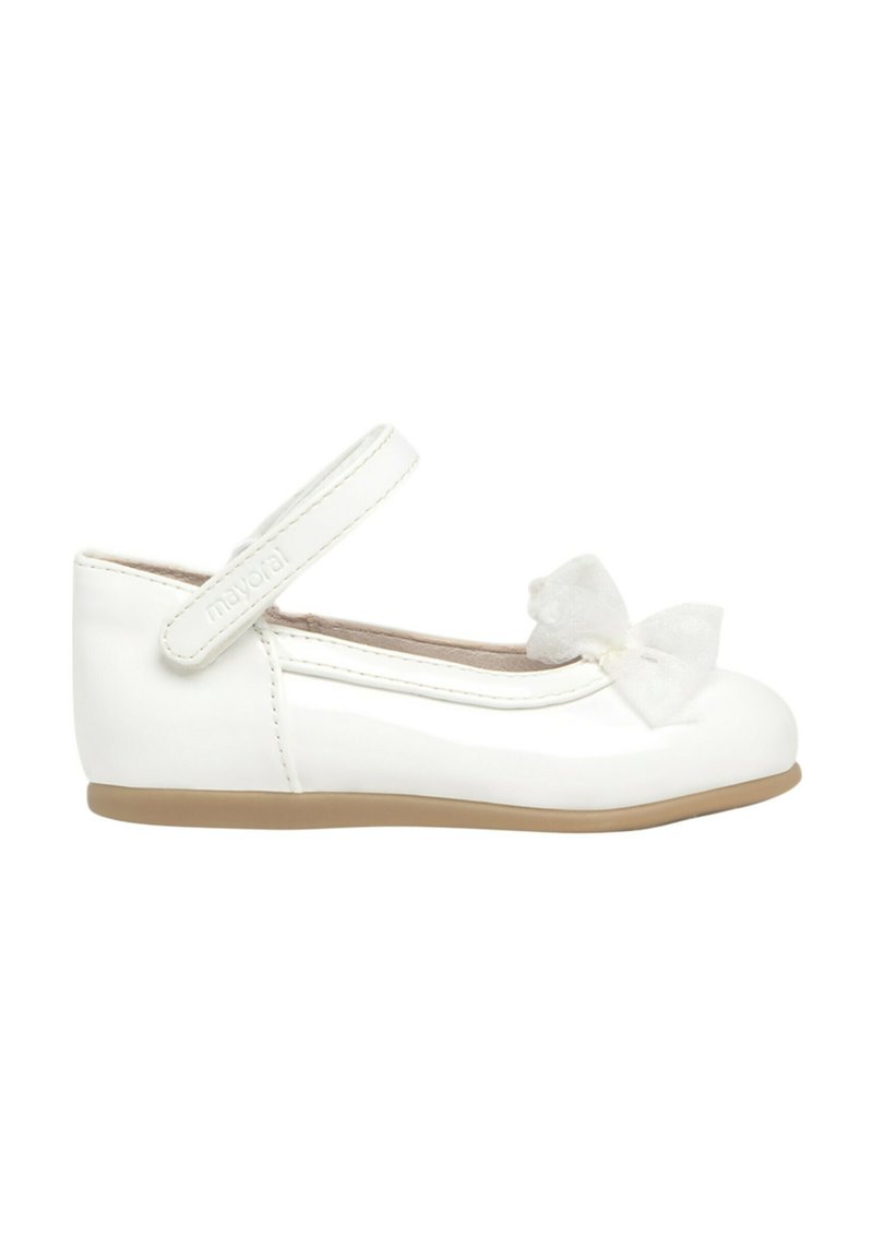 Zapato de bailarina de charol blanco con puntera redonda, cinturilla al tobillo y un lazo decorativo de tul en la parte delantera. Suela de goma de color beige claro.