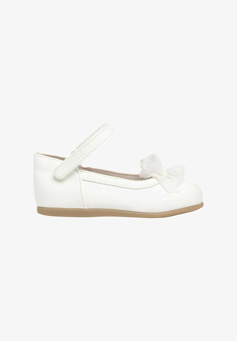 Zapato de bailarina de charol blanco con puntera redonda, cinturilla al tobillo y un lazo decorativo de tul en la parte delantera. Suela de goma de color beige claro.