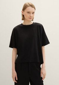 Schwarzes Baumwoll-T-Shirt mit entspannter Passform, kurzen Ärmeln und Rundhalsausschnitt. Glatte Textur, minimalistisches Design und keine Muster oder Akzente.
