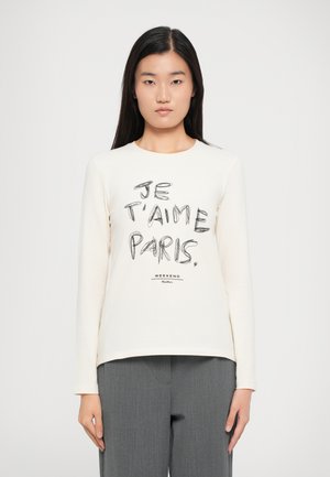 T-shirt a maniche lunghe di colore crema con la scritta nera "JE T'AIME PARIS" e un logo in basso. Tessuto morbido con vestibilità rilassata.