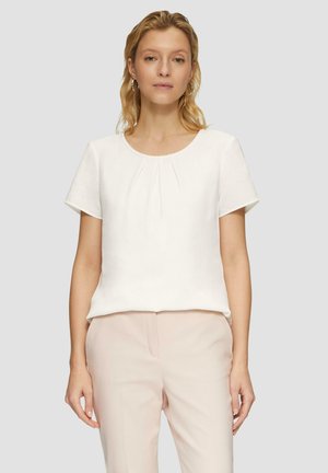 Weißes Kurzarmblusenshirt mit Rundhalsausschnitt und dezenten Falten an der Vorderseite. Weicher Stoff, einfaches Design, kombiniert mit hellrosa Hosen.