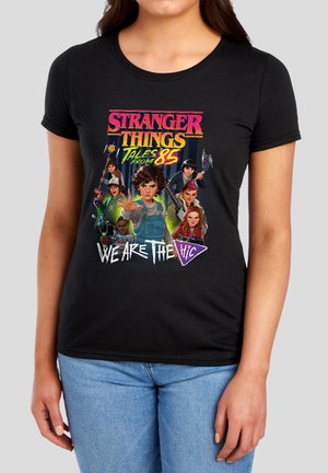 Black t-shirt with colorful "Stranger Things Tales from '85" graphic showing seven characters and "We Are The H.i.c." text.