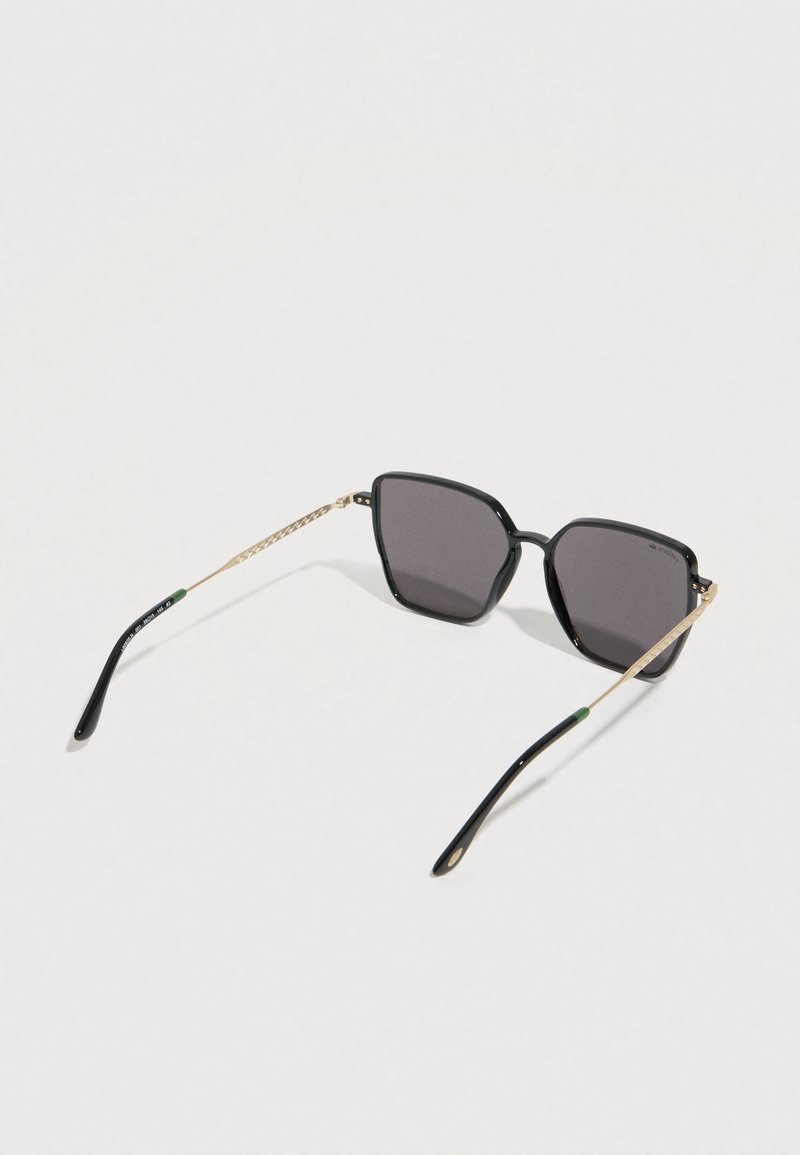 Sorte firkantede solbriller med mørke linser. Guldfarvede metalaccenter på stængerne med en struktureret mønster og en grøn spids.