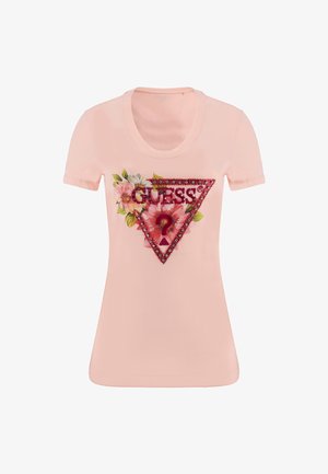 Camiseta de manga corta rosa con un diseño floral y un logo triangular de "GUESS" con acentos rojos y pedrería alrededor de los bordes.