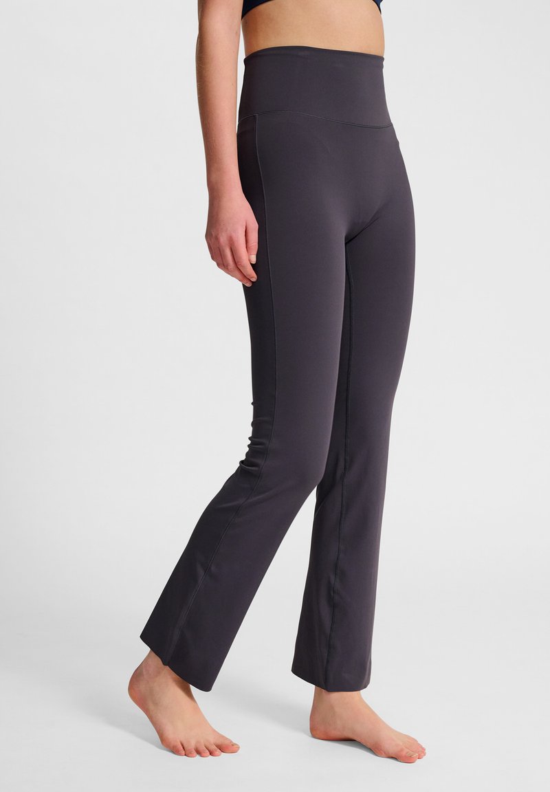 Hög midja, mörkgrå leggings med en slät textur, figurnära design och en lätt utsvängning vid ankeln, med flatlock-sömmar.