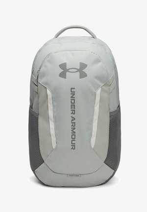 Grijze Under Armour rugzak met een handvat bovenaan, zijvakken van mesh en een verticaal logo op het voorpaneel.