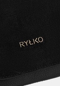 Crna ante površina s teksturiranim finišom, s zlatnim logotipom "RYŁKO". Dizajn je minimalistički i elegantan.