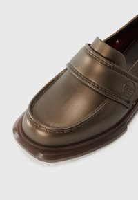 Brown leather loafers with a rounded toe, a stitched accent and a logo detail on the band. Features a brown textured sole.