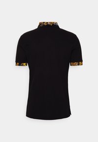 Svart kortärmad polo med ett mönstrat gult och guld kantband på kragen och ärmarna. Slätt bomullstyg med avslappnad passform.