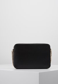 Borsa a tracolla nera rettangolare realizzata in materiale texturizzato con una tracolla in catena dorata. Design semplice con angoli arrotondati.