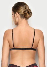 Soutien-gorge nero con spalline sottili, fascia posteriore piatta e hardware regolabile. Presenta dettagli in pizzo sulla parte inferiore. Texture liscia.