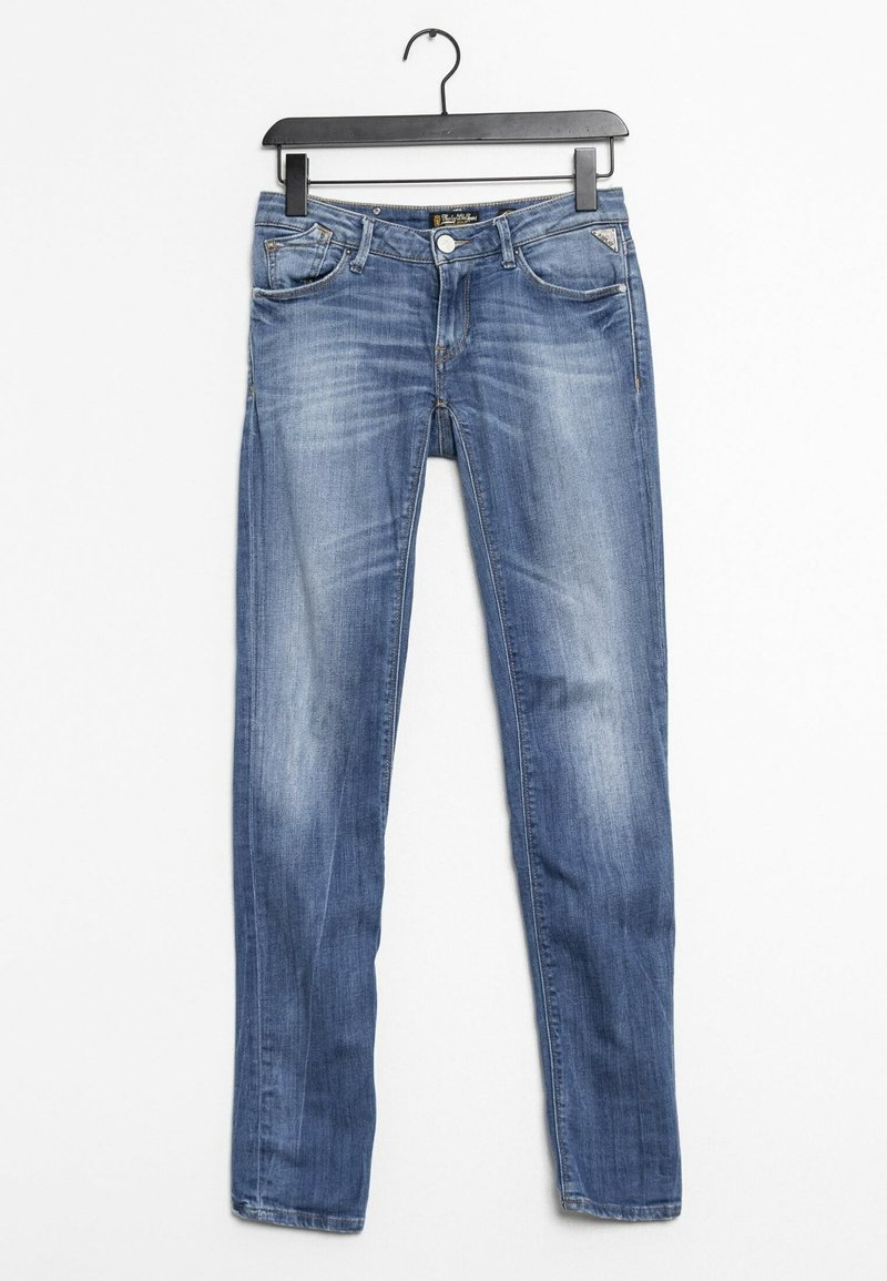 Siniset haalistuneet slim fit -farkut roikkuvat mustassa muovihatassa valkoista taustaa vasten.