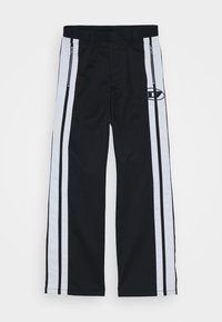 Pantalon noir avec de larges bandes blanches sur les côtés bordées de fines lignes noires, poches avant zippées et petit logo rond sur la cuisse droite.