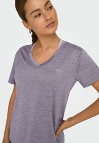 Paarse, korte mouwen V-hals t-shirt gemaakt van een gestructureerde, lichte stof. Subtiele logo-detail aan de voorzijde, links.