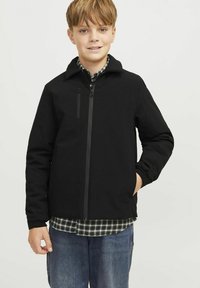 Svart zip-up jacka med hög krage och elastiska cuffs. Materialet är mjukt med en slät struktur. Har en bröstficka och är lager på lager över en rutiga skjorta.