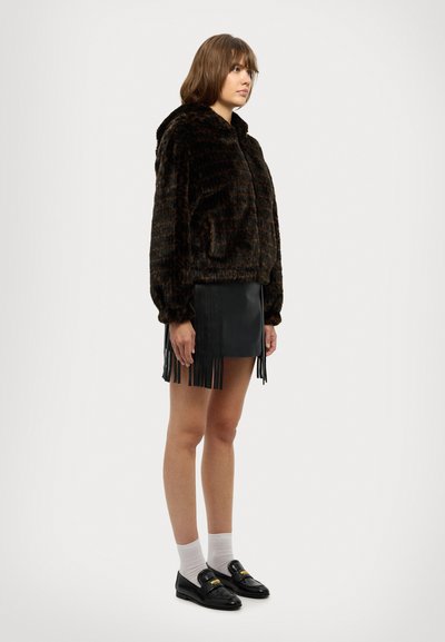 Brown faux-fur hooded jacket with a textured surface, paired with a black fringed leather mini skirt and black loafers with gold accents.