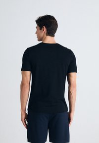 Schwarz eng anliegendes T-Shirt mit kurzen Ärmeln, hergestellt aus weichem Stoff, mit klassischem Rundhalsausschnitt, minimalen Nähten und glatter Textur.