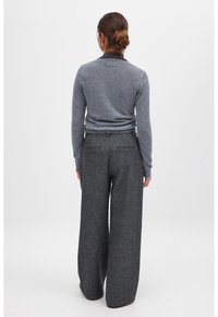 Grijze gebreide trui in combinatie met grijze wijde, textuurwol broek, met twee achterzakken en een gladde tailleband.