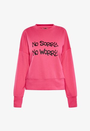 Felroze sweatshirt met lange mouwen en zwarte tekst met de woorden "No Sorry No Worry" in een vet, graffiti-stijl lettertype op de voorkant.