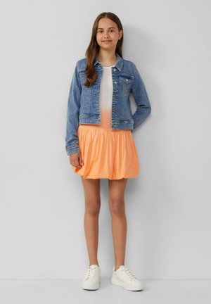 Veste en denim avec un lavage bleu clair, jupe orange évasée et baskets blanches. Design simple sans motifs ni accents.