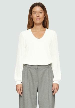 Witte V-hals trui met verticaal geribde mouwen, gecombineerd met hoge taille grijze broeken. Zachte textuur, comfortabele pasvorm.