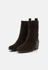 Pair of dark brown suede ankle boots with low heels, pull tabs, and textured back detailing on a plain light background.