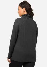Pullover grigio scuro a maniche lunghe con colletto alto, caratterizzato da una vestibilità morbida e spacchi laterali. Realizzato in tessuto morbido e leggero.
