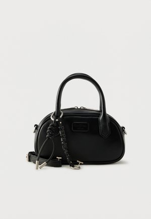 Sac à main arrondi en cuir noir avec doubles poignées, bandoulière amovible et porte-clés de marque, posé sur une surface blanche.