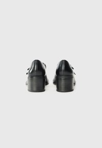 Black leather shoes with a rounded toe, short block heel, and thin laces. Smooth texture with a sleek silhouette and minimal detailing.