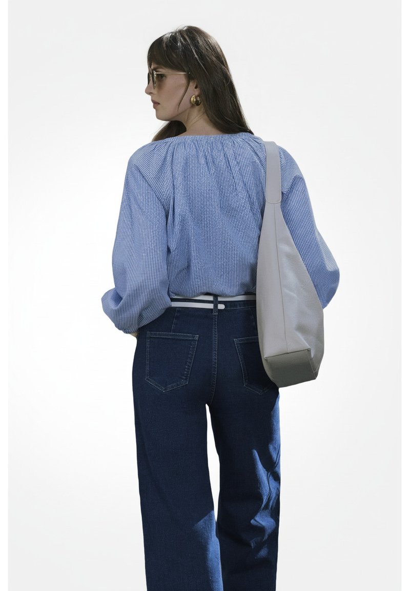 Blauw-wit gestreepte blouse met pofmouwen, gecombineerd met donkerblauwe wijde jeans en een lichtgrijze schoudertas.