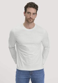 Witte langemouwen t-shirt van katoen, met een geribbelde ronde hals en aansluitende mouwen, gecombineerd met blauwe jeans.