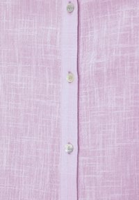 Chemise en lin rose clair présentant un tissu texturé, avec cinq boutons ronds et brillants sur le devant et un tissage vertical subtil.