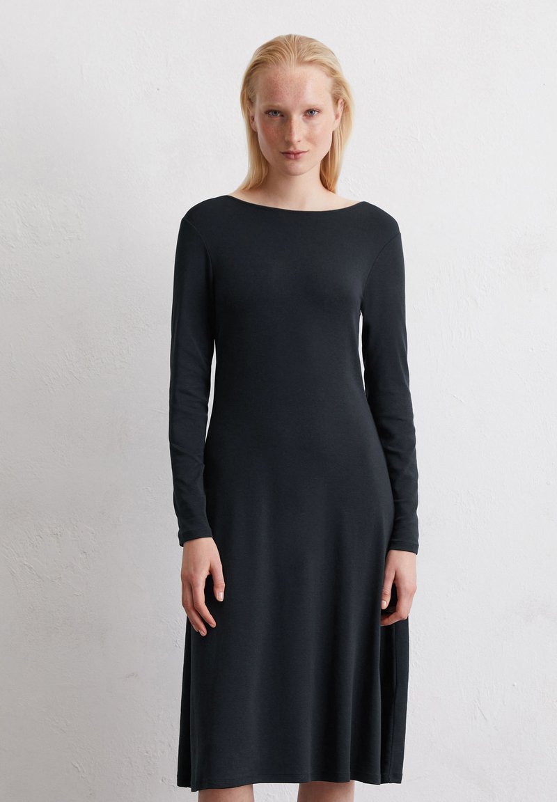Schwarzes Langarmkleid aus weichem Stoff mit eleganter, fließender Form, das einen weiten Ausschnitt und seitliche Schlitze für optimale Bewegungsfreiheit bietet.
